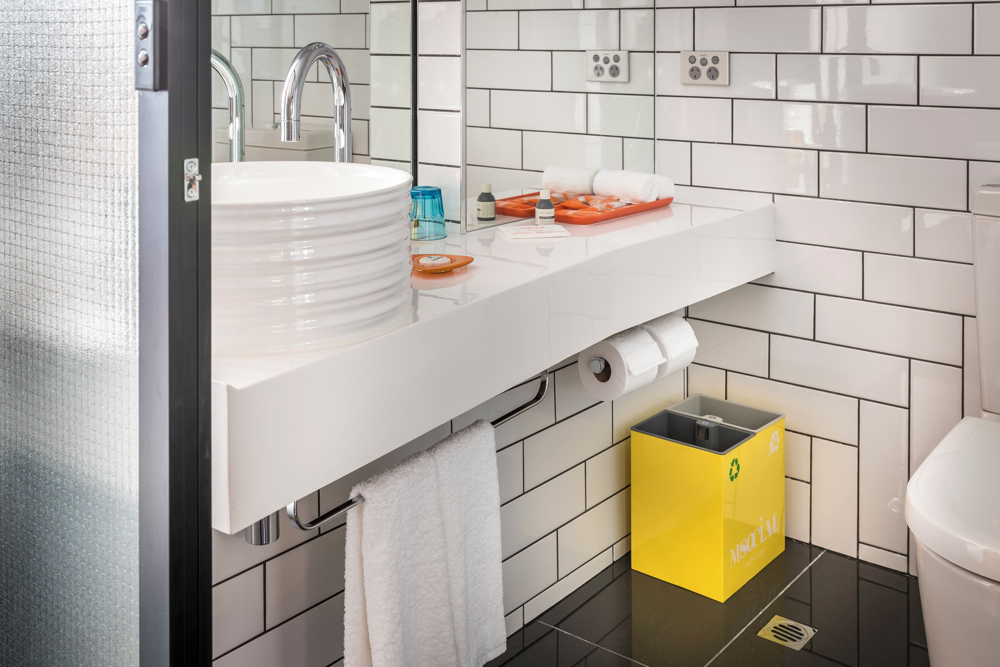 A modern bathroom with a white sink, mirror, and tiled walls.