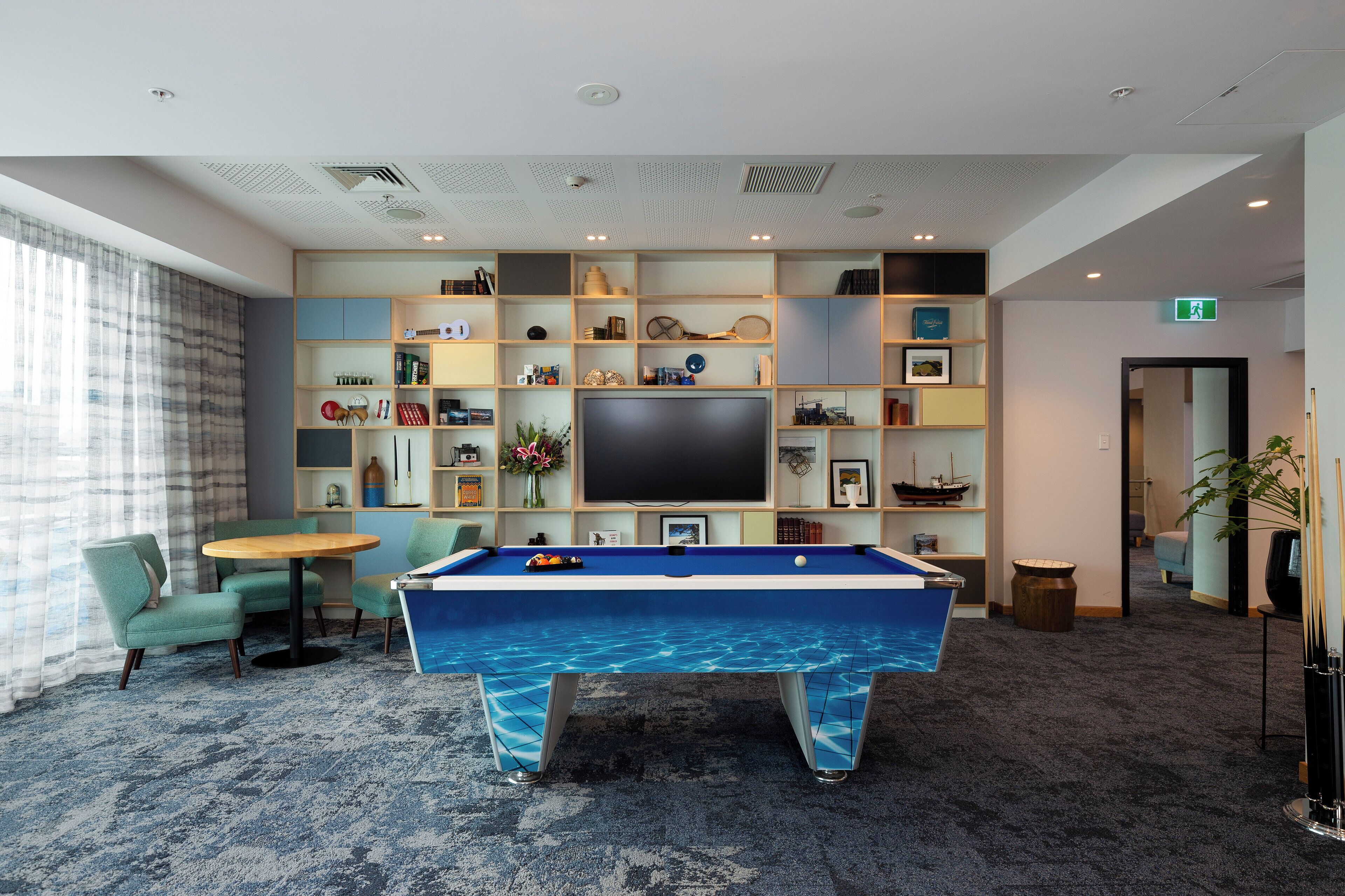 A pool table with a blue marble design, surrounded by teal chairs and a small round table.