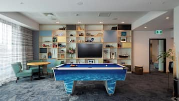 A pool table with a blue marble design, surrounded by teal chairs and a small round table.