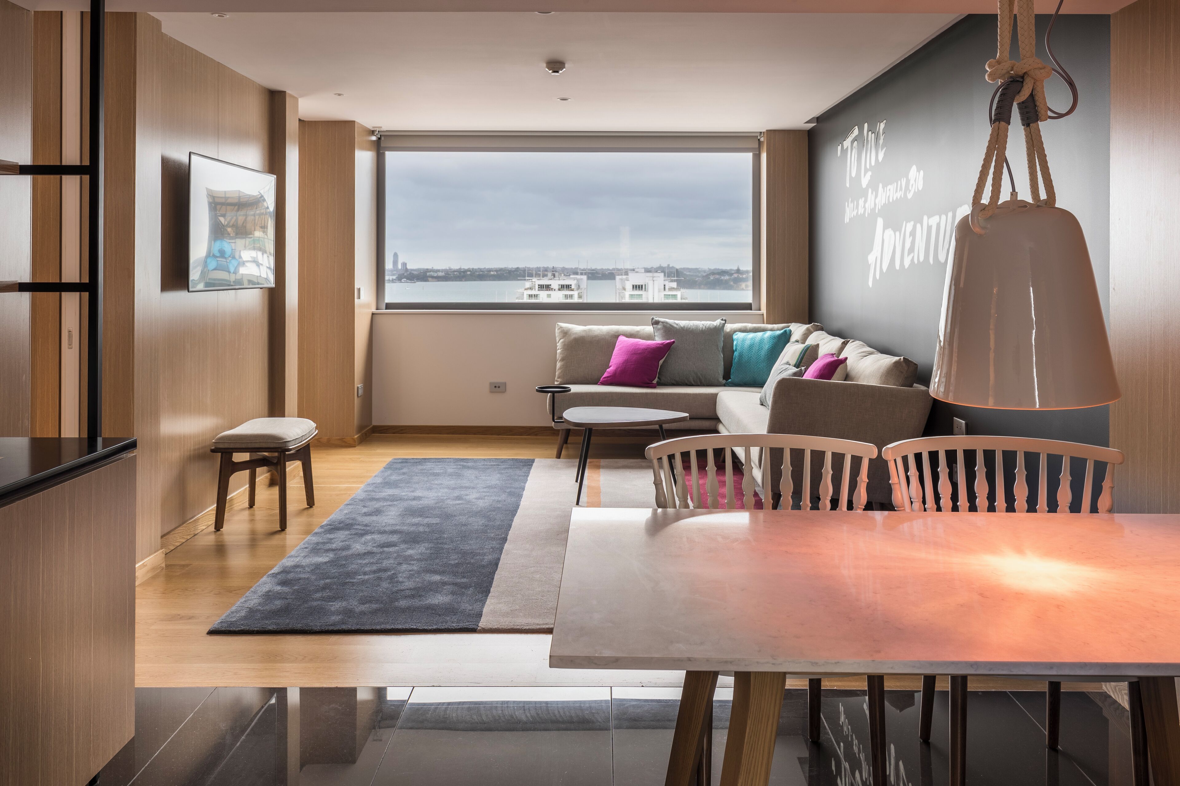 Una sala de estar moderna con un ventanal grande, un sofá, una mesa de comedor y una zona de cocina.