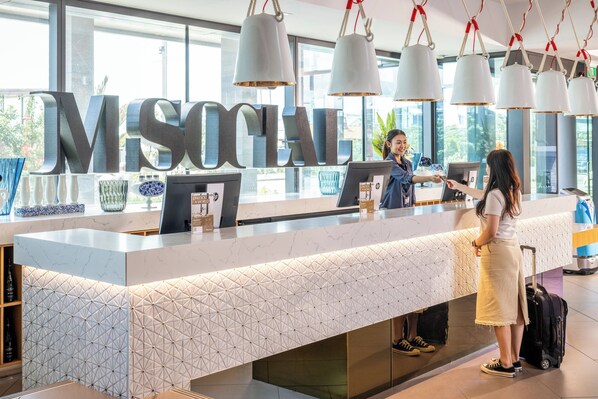 A reception desk with a large 'MS SOCIAL' sign, a modern design with geometric patterns, and a view of the outdoors through large windows.