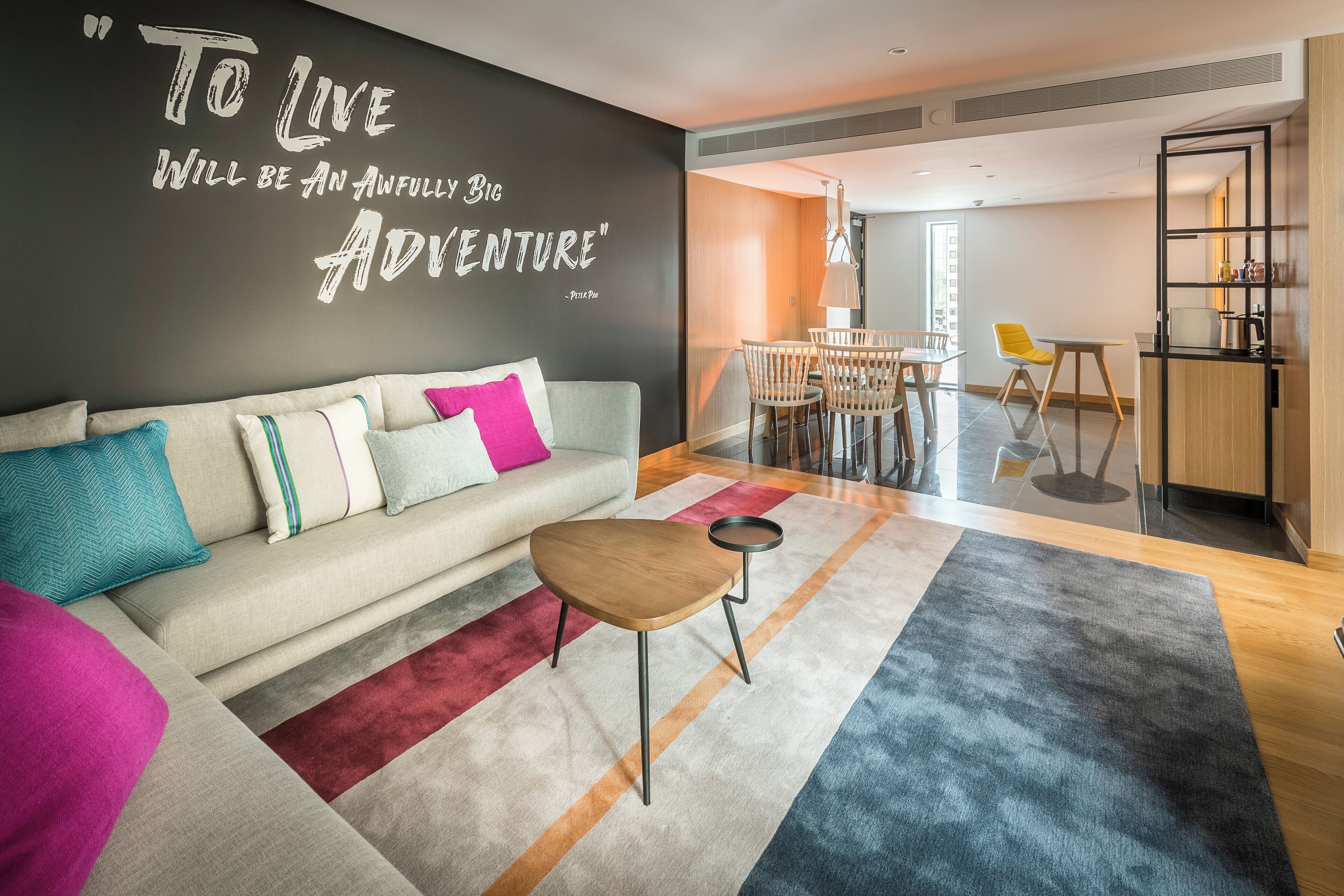 Una sala de estar moderna con un sofá, una mesa de centro, un comedor con sillas y una zona de cocina con un estante.