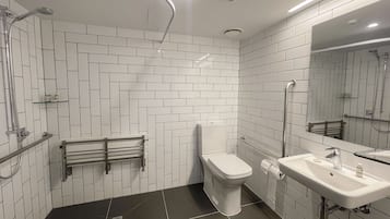 Casa de banho moderna com azulejos brancos em padrão herringbone, chão em mosaico preto, sanita, lavatório e zona de duche.