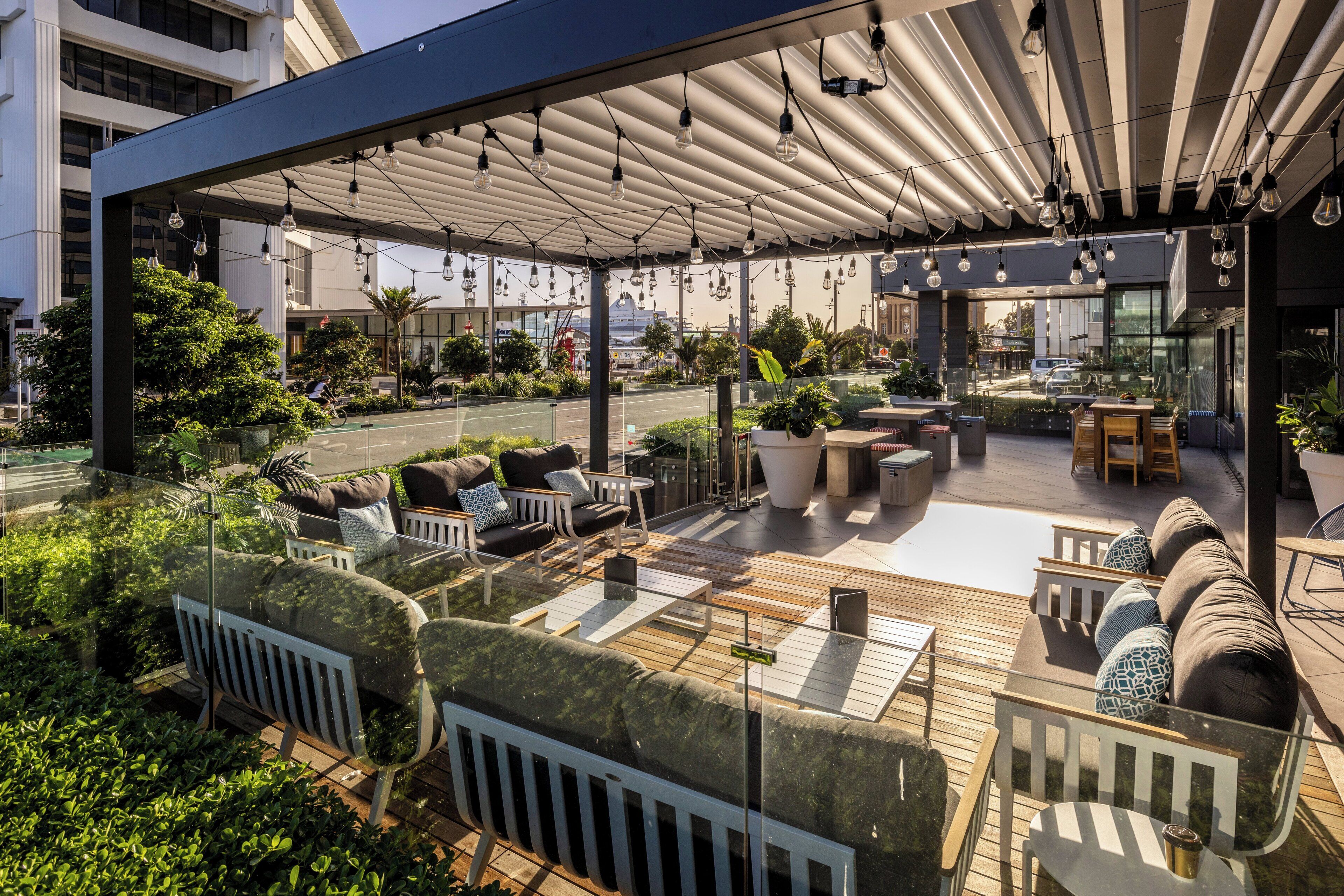 An outdoor seating area with modern furniture, a covered patio, and potted plants.