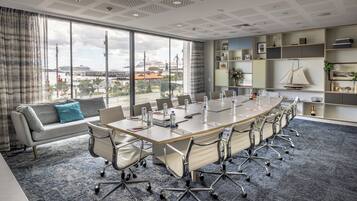 A modern conference room with a large table, chairs, and a sofa.