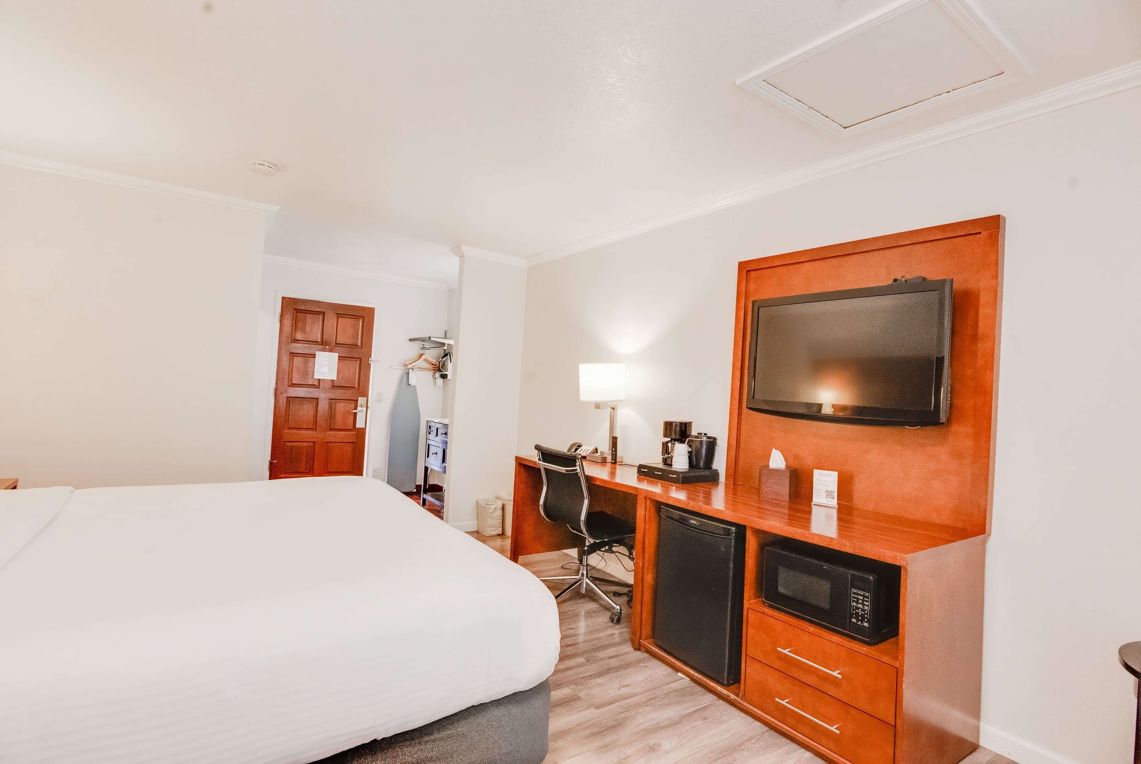 Habitación de hotel con cama, escritorio con computadora, televisor y microondas.