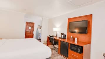 Habitación de hotel con cama, escritorio con computadora, televisor y microondas.