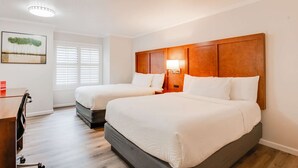 A hotel room with two beds, a desk, a chair, a lamp, and a painting on the wall. - Ramada by Wyndham Mountain View (Mountain View)