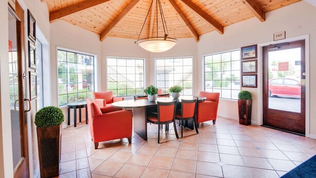 A dining area with a wooden ceiling, large windows, and red chairs. - Ramada by Wyndham Mountain View (Mountain View)