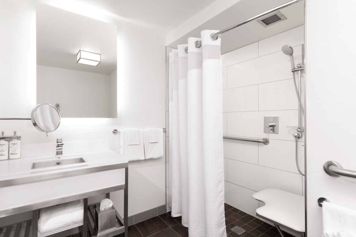 A modern bathroom with a white sink, mirror, and shower area.