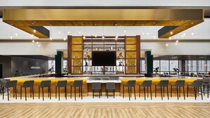 A modern bar area with a long counter, multiple bar stools, and a large flat-screen TV. - Holiday Inn Chicago Dwtn - The Mart by IHG (Chicago)
