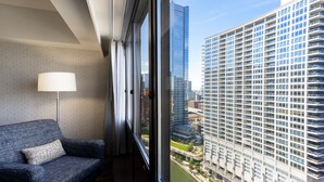 A modern hotel room with a large window, a blue sofa, and a lamp. - Holiday Inn Chicago Dwtn - The Mart by IHG (Chicago)