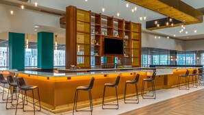A spacious lobby with a central bar area, seating, and a large window offering a city view. - Holiday Inn Chicago Dwtn - The Mart by IHG (Chicago)