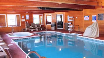 Ein Hallenbad mit Holzbalkendecke, einem Rettungsschwimmerstuhl und einer überdachten Sitzbank.
