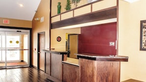 A reception area with a wooden reception desk, a glass door entrance, and a clock on the wall.