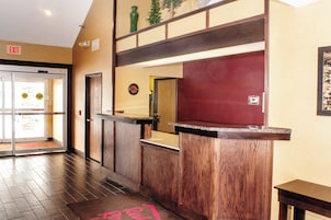 Zona de recepción con un mostrador de madera, puerta de cristal de entrada y un reloj en la pared.