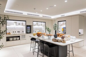 A modern kitchen with a central island, bar stools, and built-in appliances.