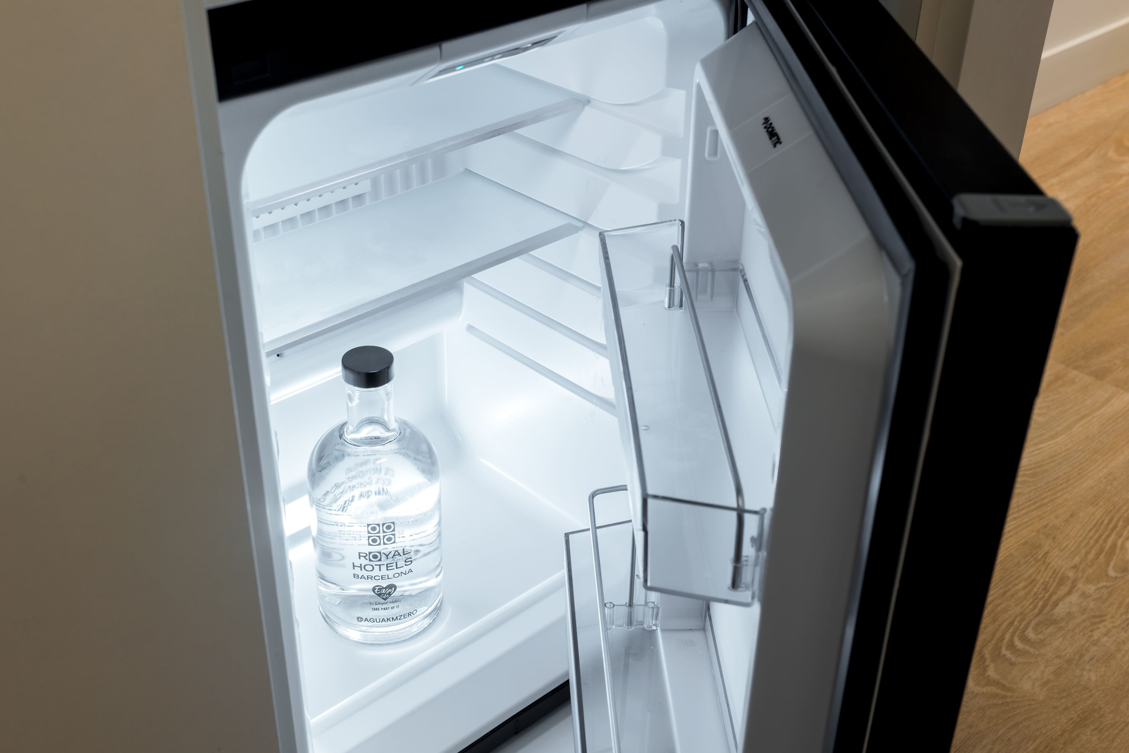 An open refrigerator with a bottle of Royal Hawaiian brand water on the door shelf.