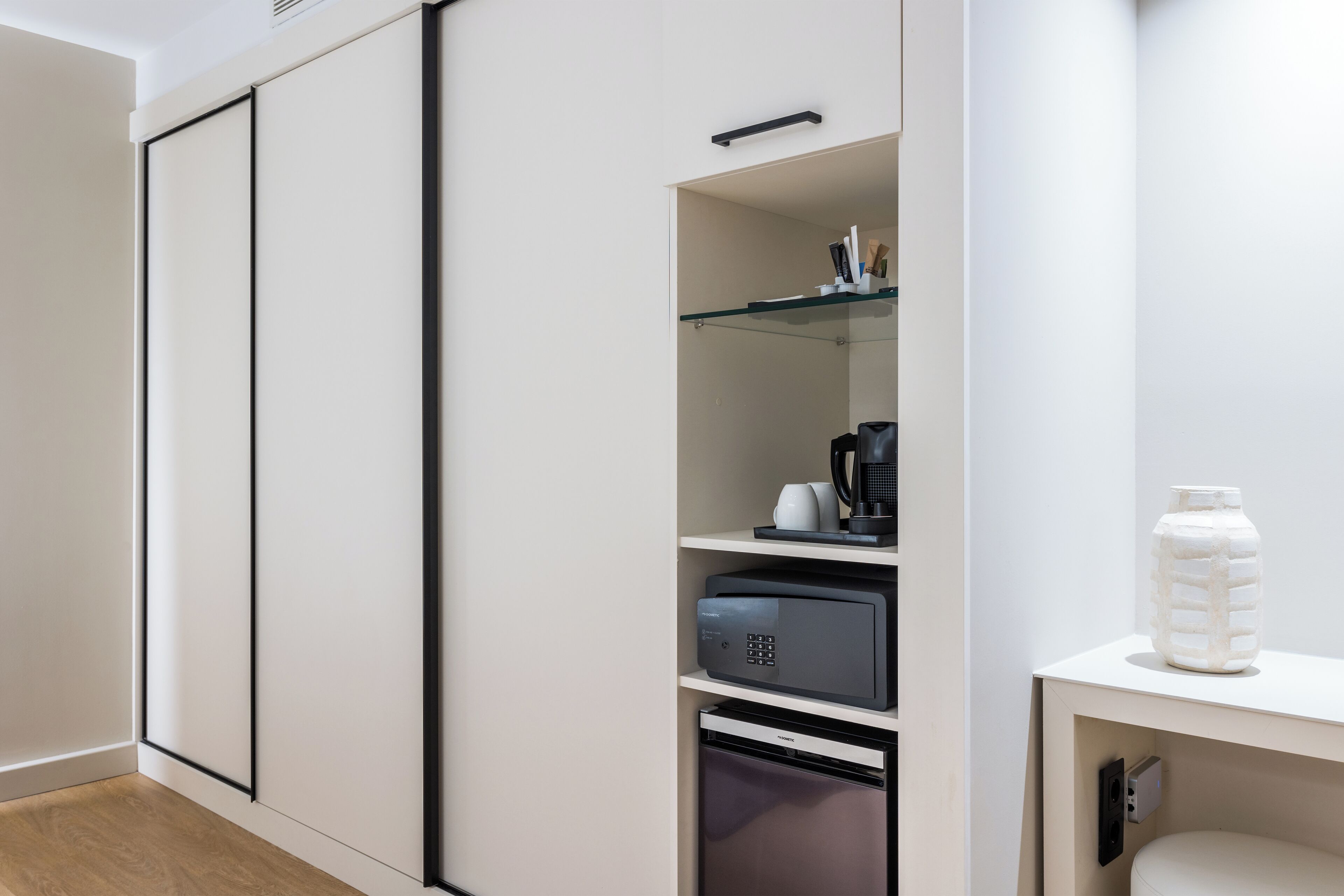 A modern kitchen with a microwave, coffee maker, and a water dispenser on a white countertop.