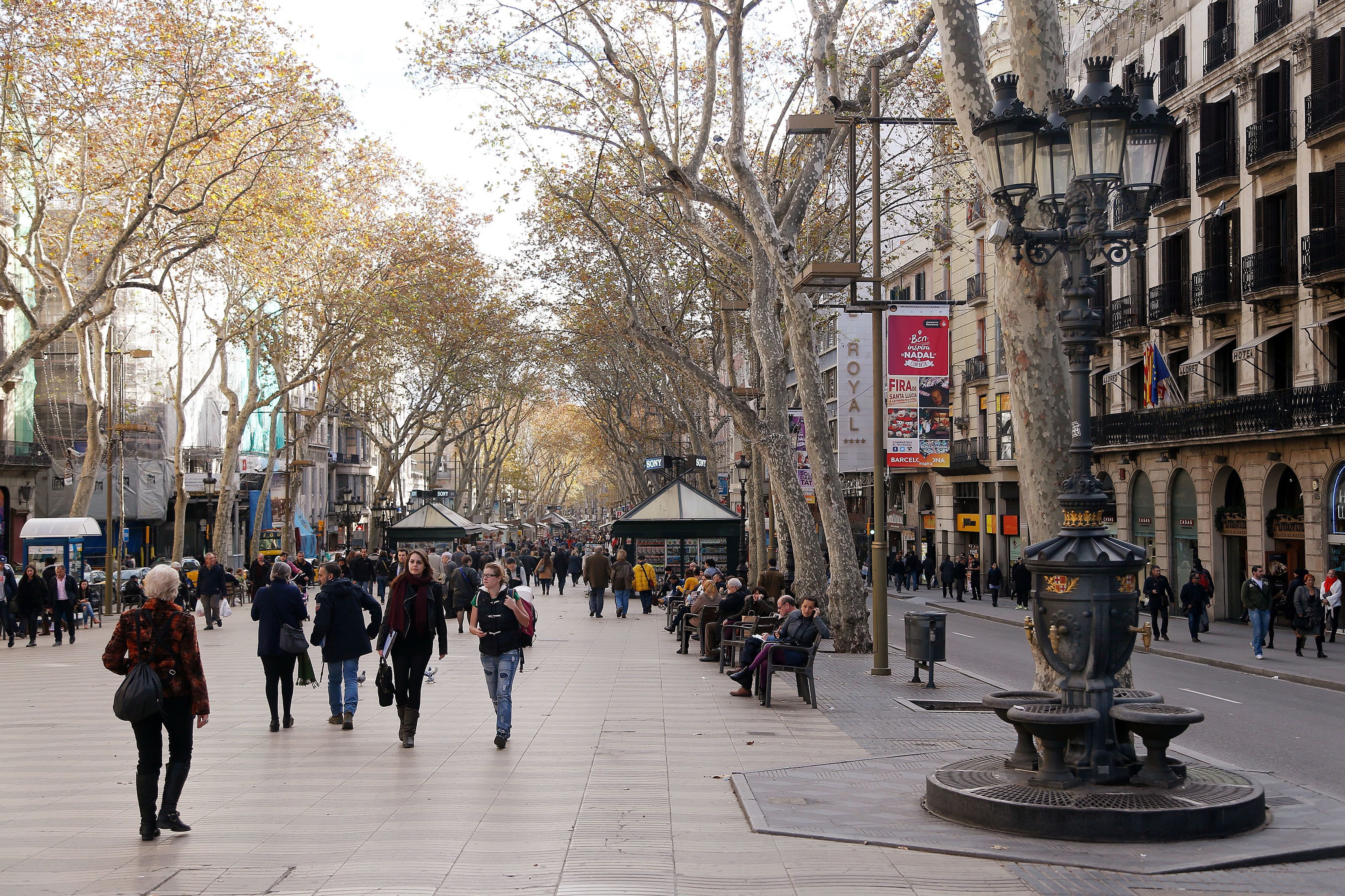 A busy urban square with pedestrians, a fountain, and historic buildings.