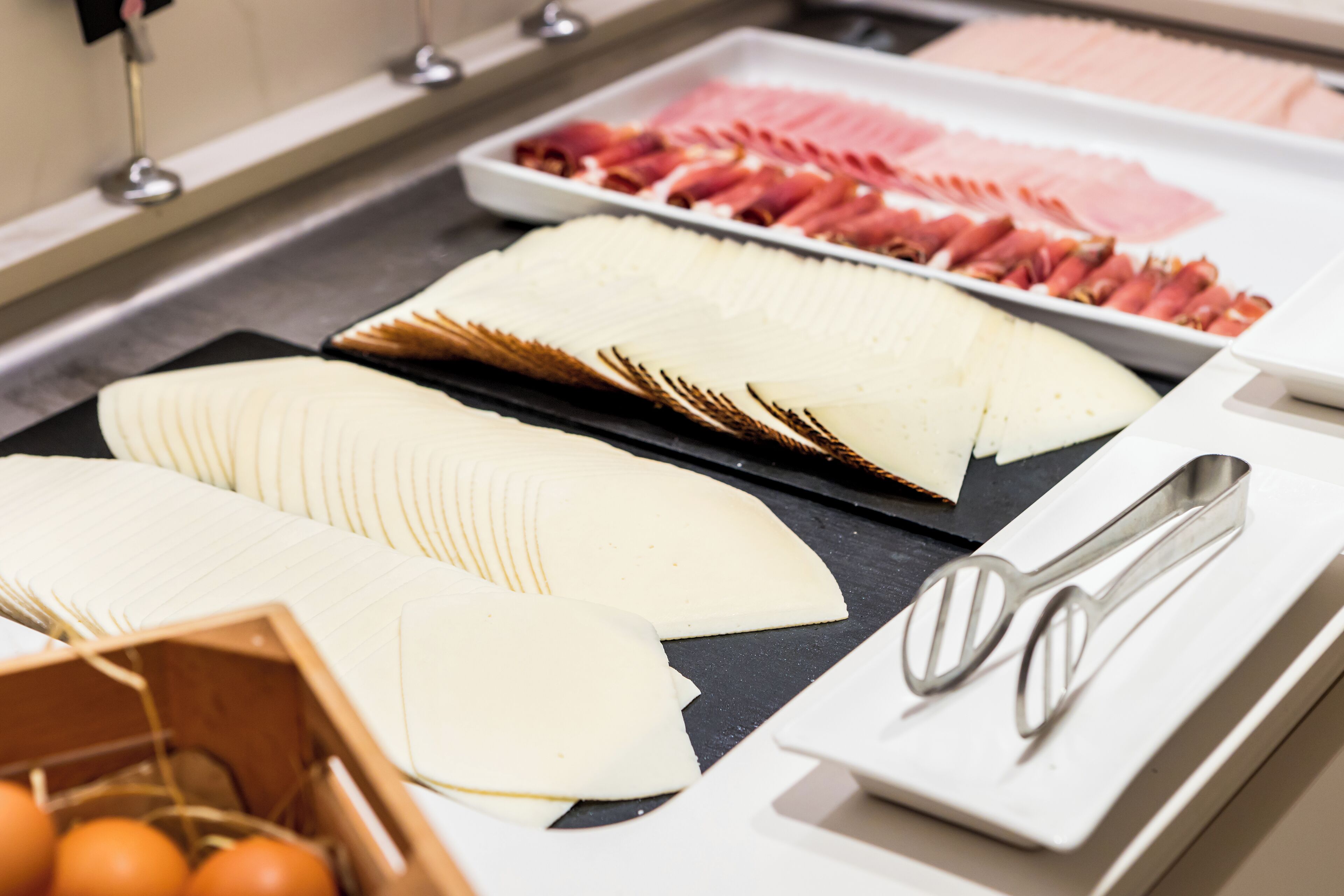 A buffet with various food items including sliced meats and cheeses.