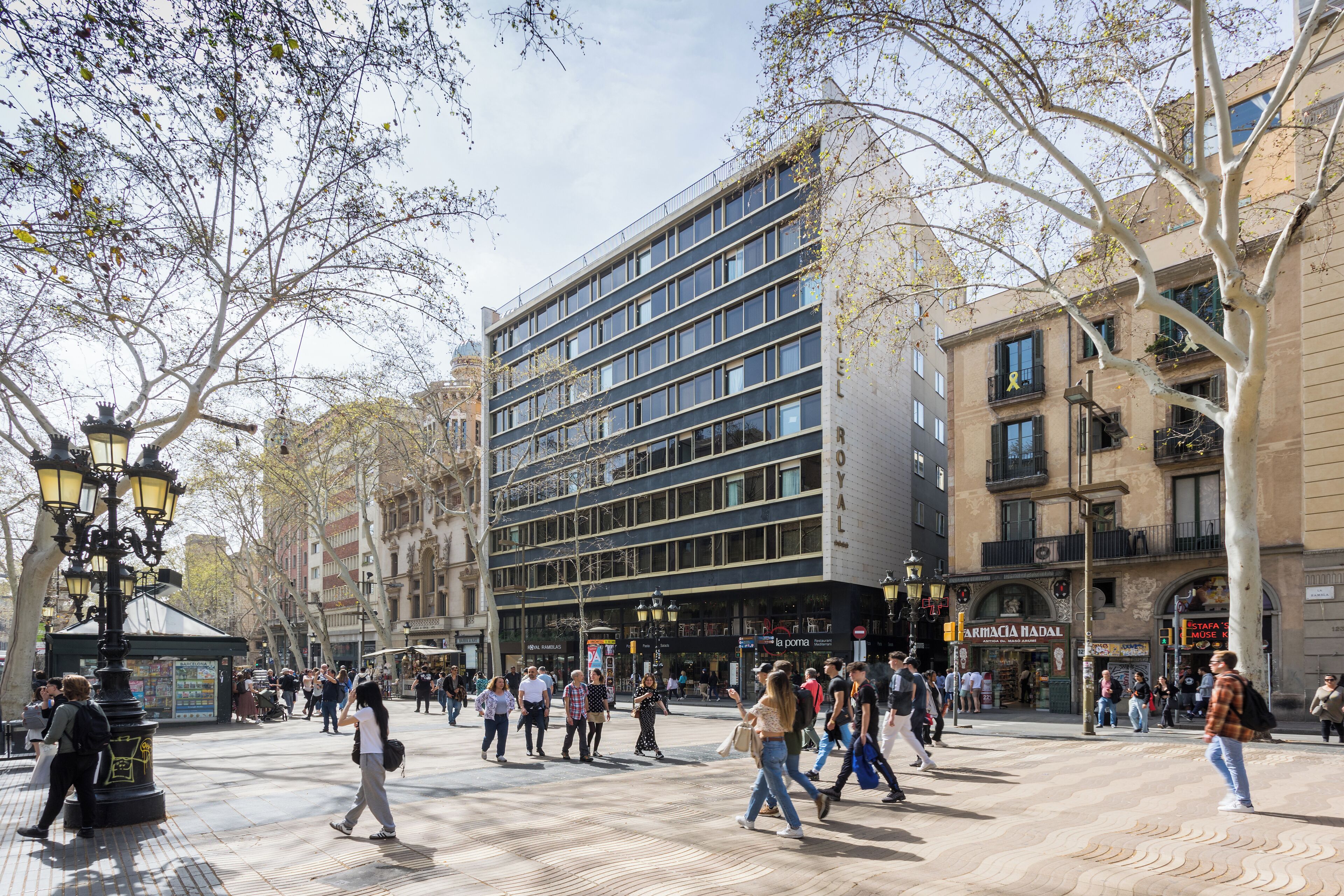 Une place animée en plein cœur de la ville, avec des piétons, un bâtiment moderne et des exemples d’architecture traditionnelle.