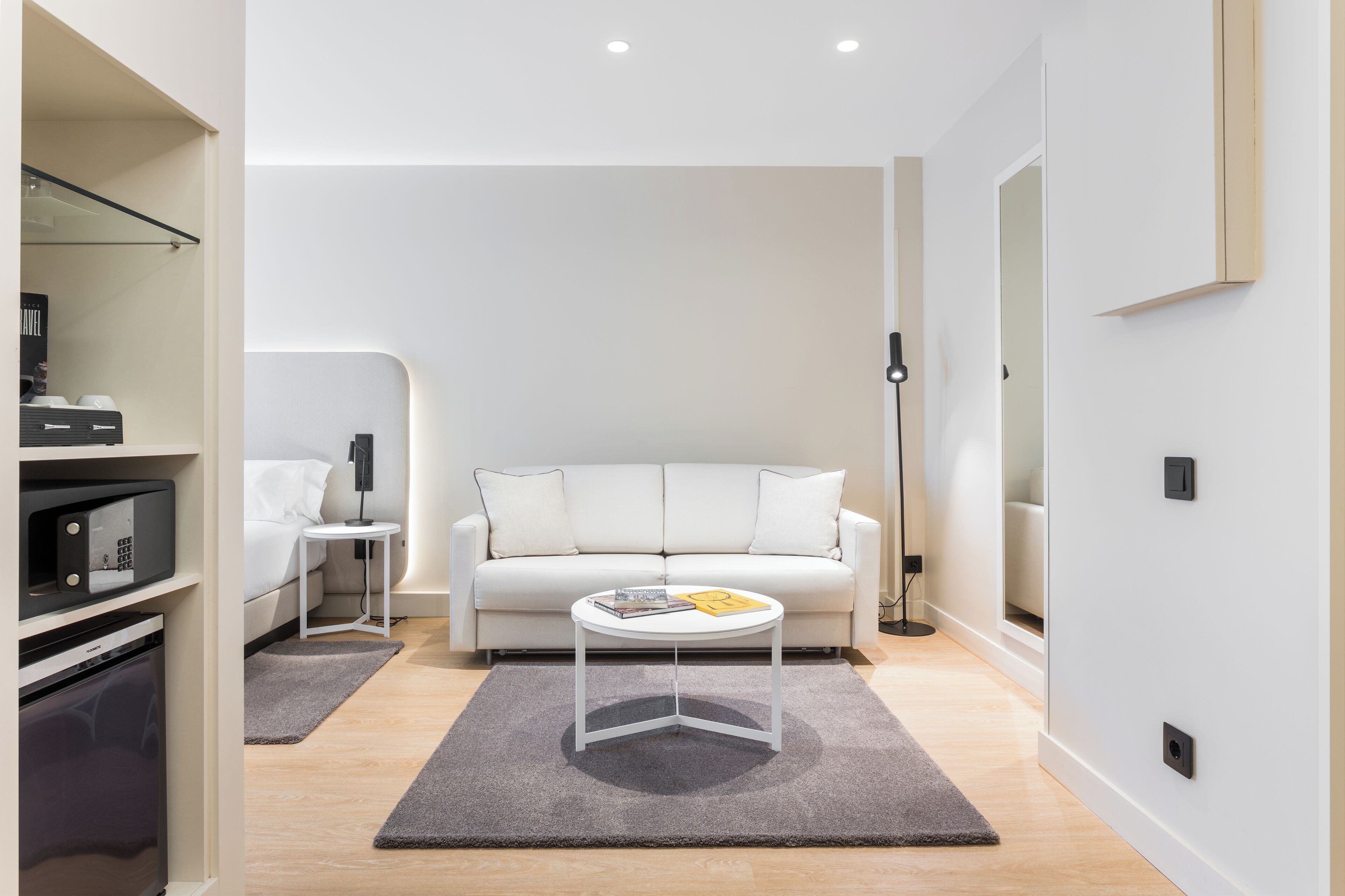 A modern living room with a white sofa, a small round table, and a grey rug.