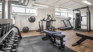 Une salle de sport équipée de machines d’exercice, d’un banc et d’haltères.