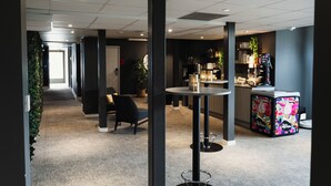 Un espace de bureau moderne comprenant un espace d’accueil, un bar et un coin salon avec une table ronde.