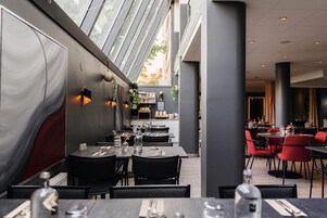 Un comedor interior con mesas y sillas, un ventanal y vistas a la calle.