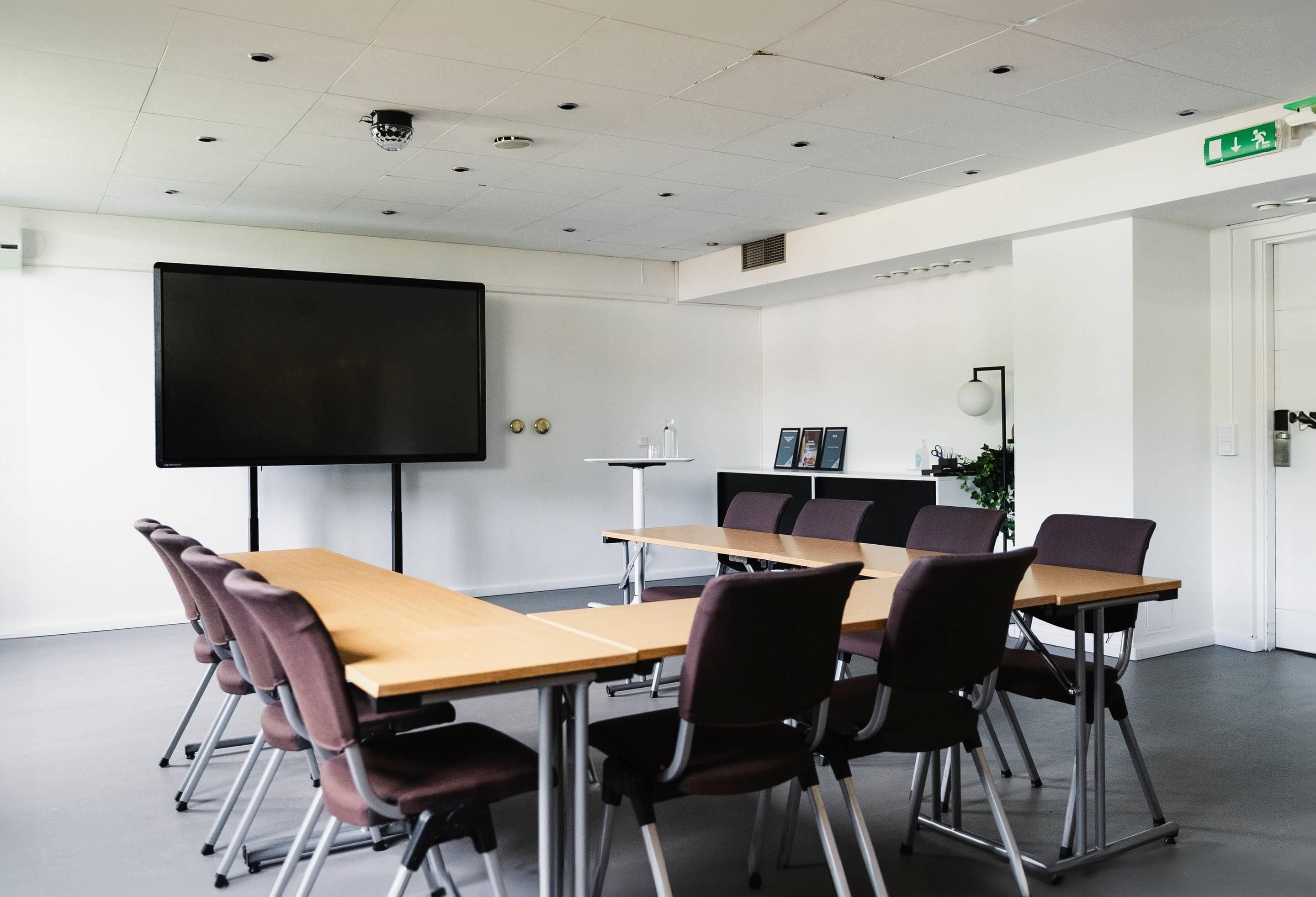 A conference room with a long table, chairs, a projector screen, and a whiteboard.