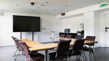 A conference room with a long table, chairs, a projector screen, and a whiteboard.