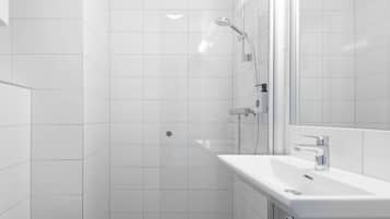 A modern bathroom with white tiles, a shower, a sink, and a mirror.