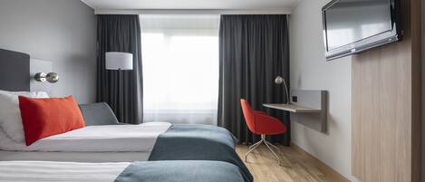 A modern hotel room with two beds, a TV, a desk, and a chair.