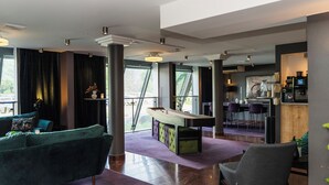 Un salon moderne avec une table de billard, un canapé vert et un coin bar avec des sièges.