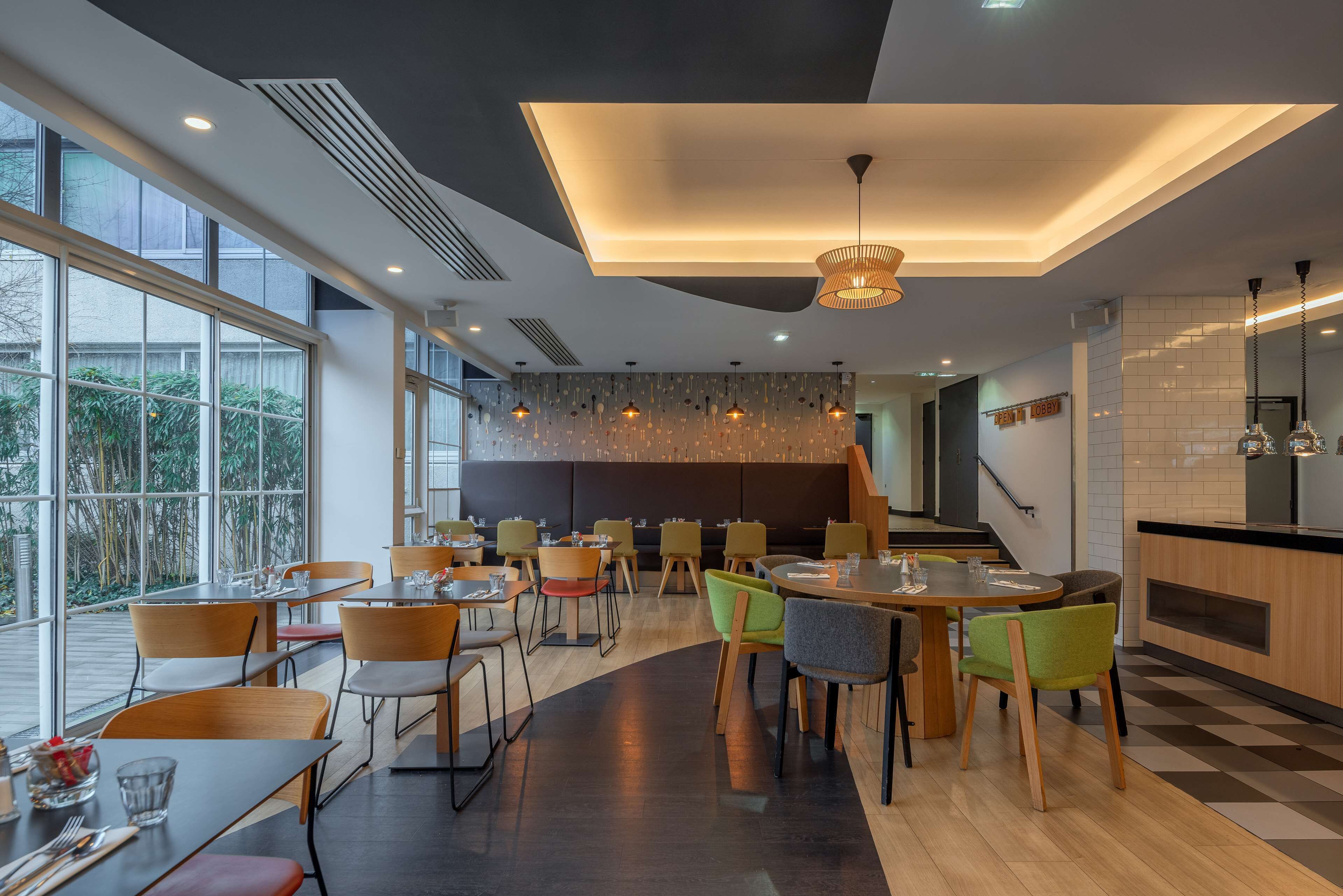 Un comedor moderno con techos altos, ventanas amplias y una combinación de sillas de madera y tapizadas.