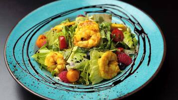 A plate of shrimp and salad with a blue rim.