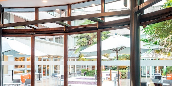 A spacious indoor area with a pool, multiple seating areas, and a view of the outdoors.
