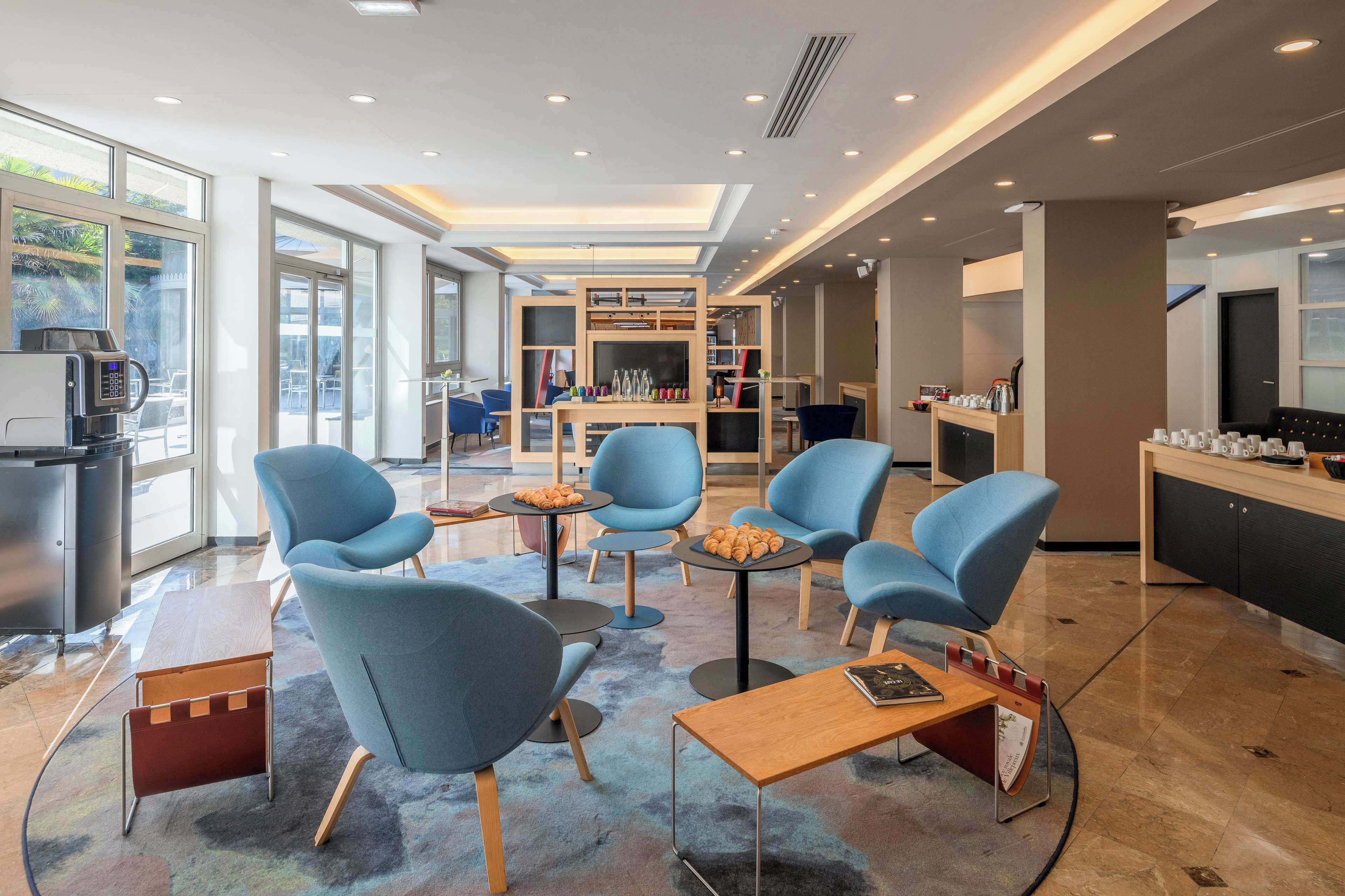 A modern lounge area with blue chairs, a coffee machine, and a fireplace.