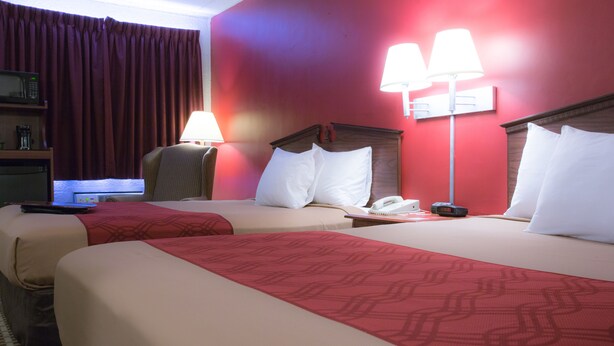 Habitación de hotel con dos camas, un escritorio con computadora, una lámpara y un teléfono.