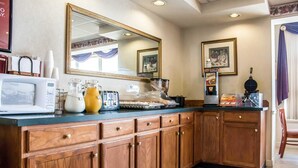 Una cocina con armarios de madera, microondas, cafetera y tostadora.