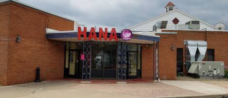 Un bâtiment avec une enseigne « HANA », une façade en briques et une entrée abritée.