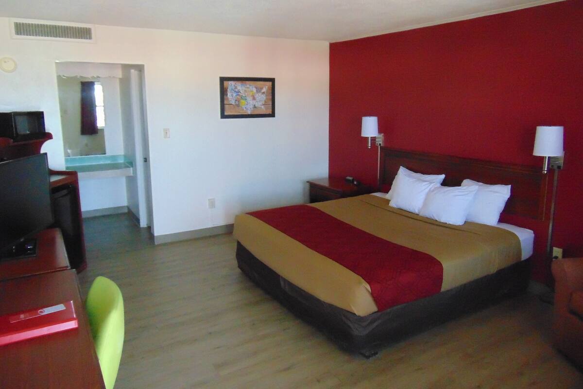A hotel room with a large bed, a desk, and a chair.