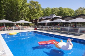 A swimming pool with inflatable toys, umbrellas, and a covered seating area. - KYRIAD MONTCHANIN - Le Creusot (Montchanin)