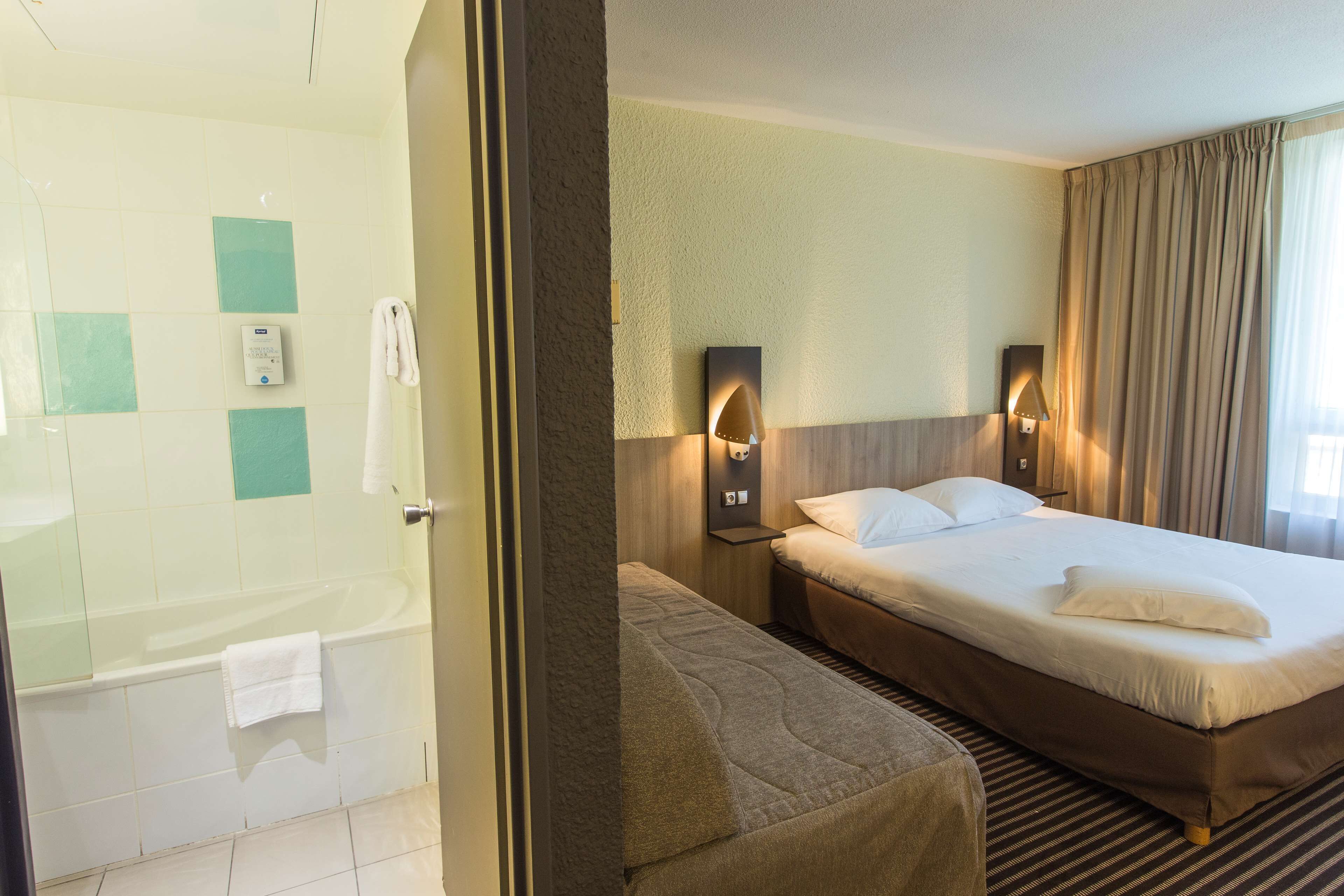 Une chambre d’hôtel équipée d’une douche, d’un lit avec une tête de lit et d’un luminaire fixé au mur.