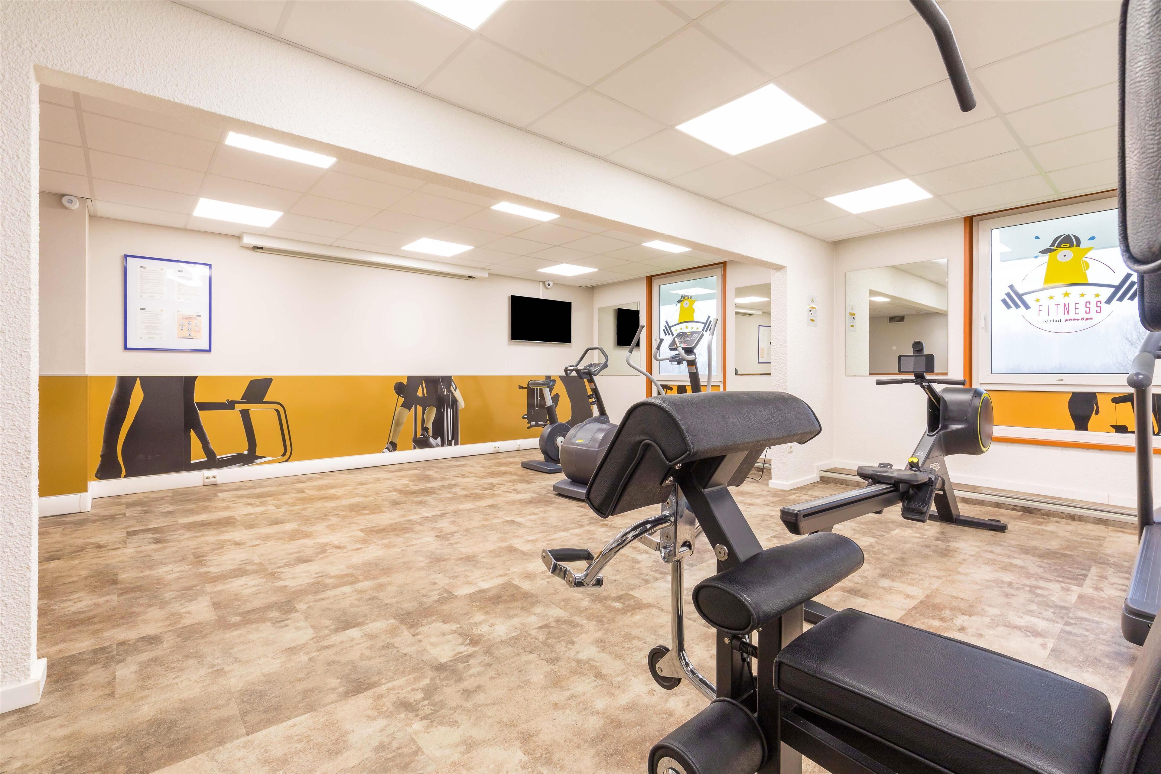A gym with exercise equipment, a mirror, and a poster on the wall.