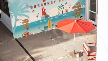 Een bord met een strandthema voor een 'Pool Burgundy Party', met afbeeldingen van palmbomen, een strandparasol en een surfboard.