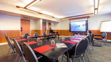 A conference room with a long table, chairs, a projector screen, and a whiteboard.