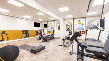 A gym with exercise equipment, a treadmill, and a mirror wall.