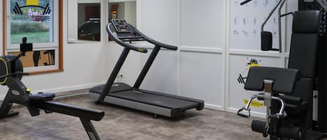 A gym with a treadmill, bench press, and weight machines.
